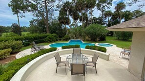 Ein Garten mit Swimmingpool, Terrassenmöbeln und einer überdachten Sitzgelegenheit.