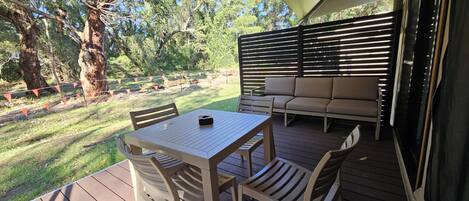 An outdoor patio with a table and chairs, a sofa, and a large umbrella providing shade.