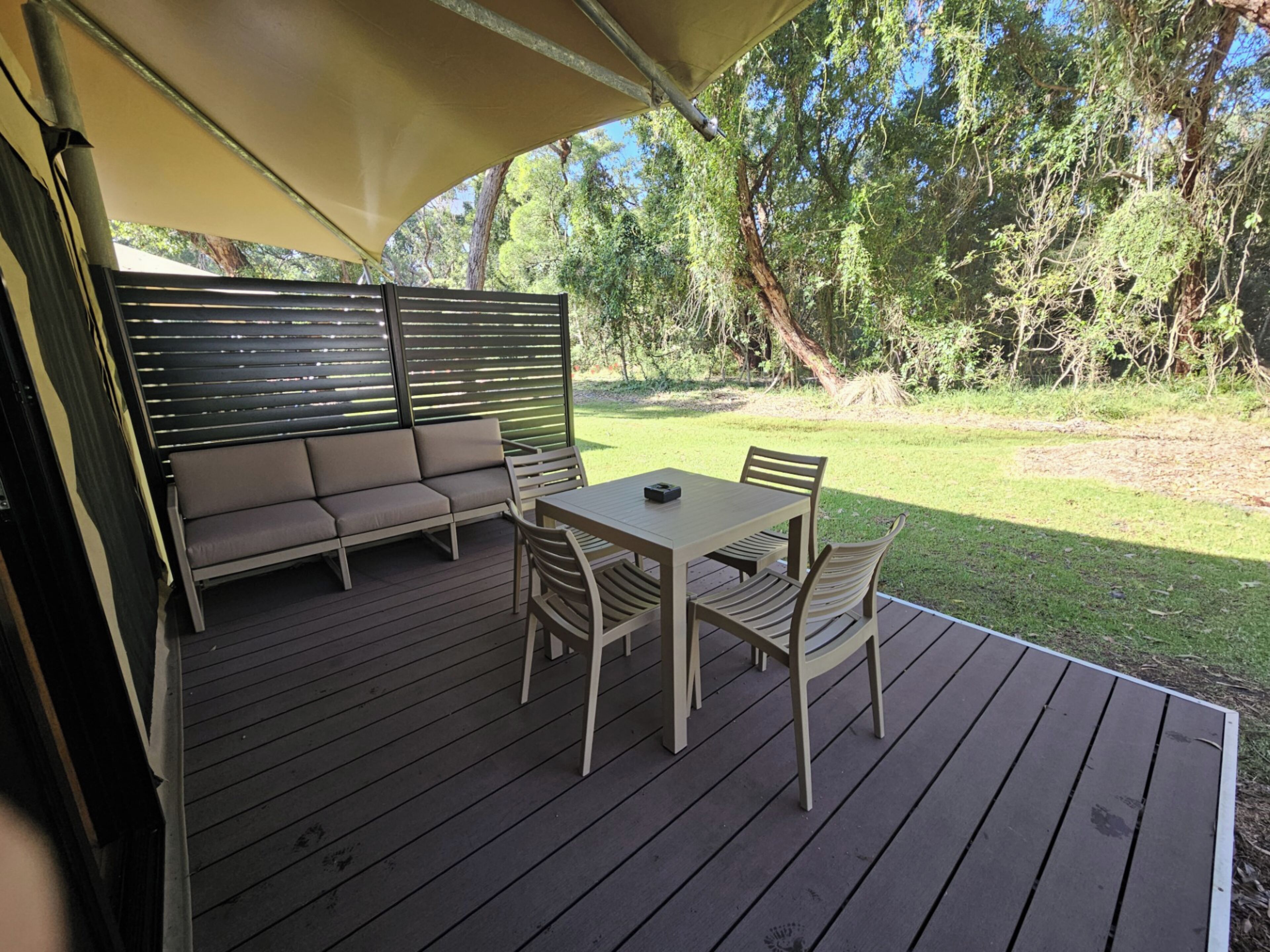 An outdoor deck with a sofa and table, surrounded by trees.