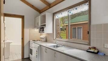 A kitchen with a window, white cabinets, a microwave, and a sink.