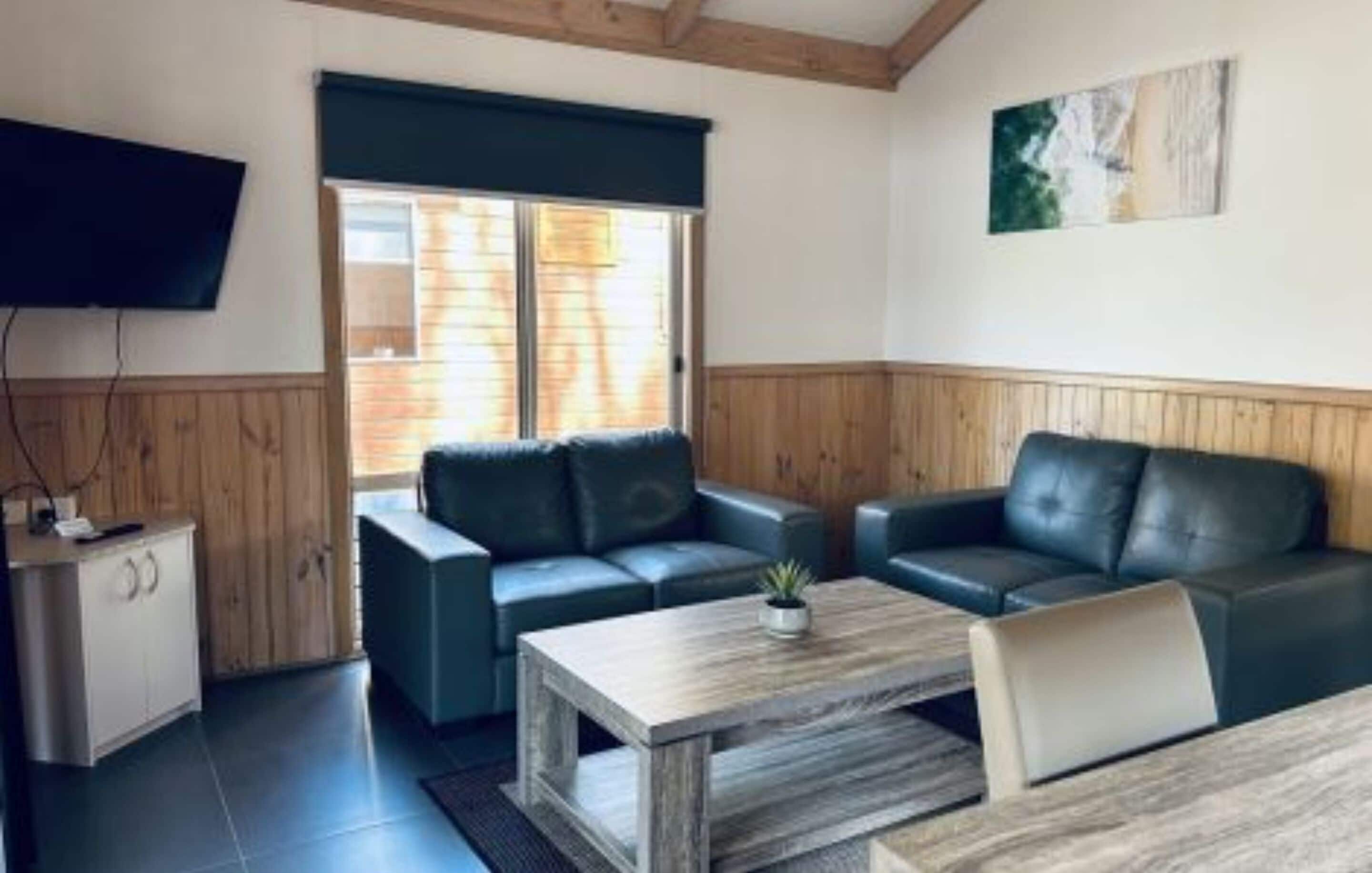 Ein möbliertes Wohnzimmer mit einer Couch, einem Couchtisch und einem an der Wand befestigten Fernseher.