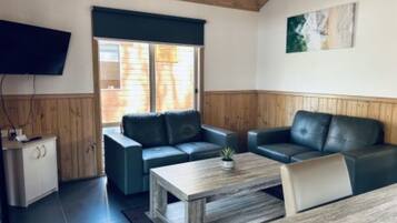 A furnished living room with a sofa, a coffee table, and a TV mounted on the wall.