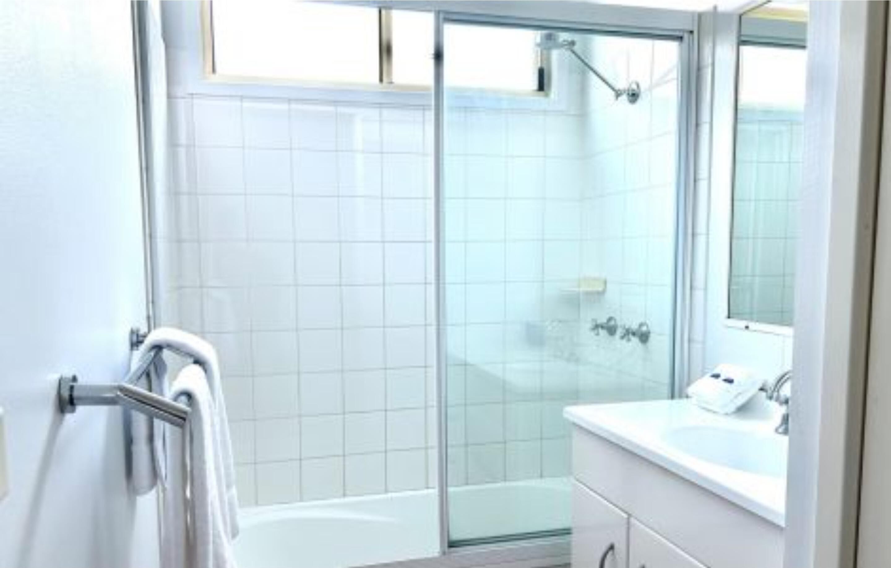 Un baño moderno con cabina de ducha de vidrio, un lavabo blanco y un espejo.