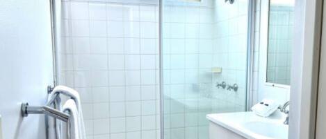 Un baño moderno con cabina de ducha de vidrio, un lavabo blanco y un espejo.