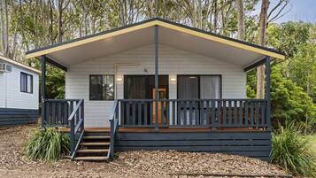 A single-story cabin with a porch, a staircase leading to the entrance, and a small deck area.