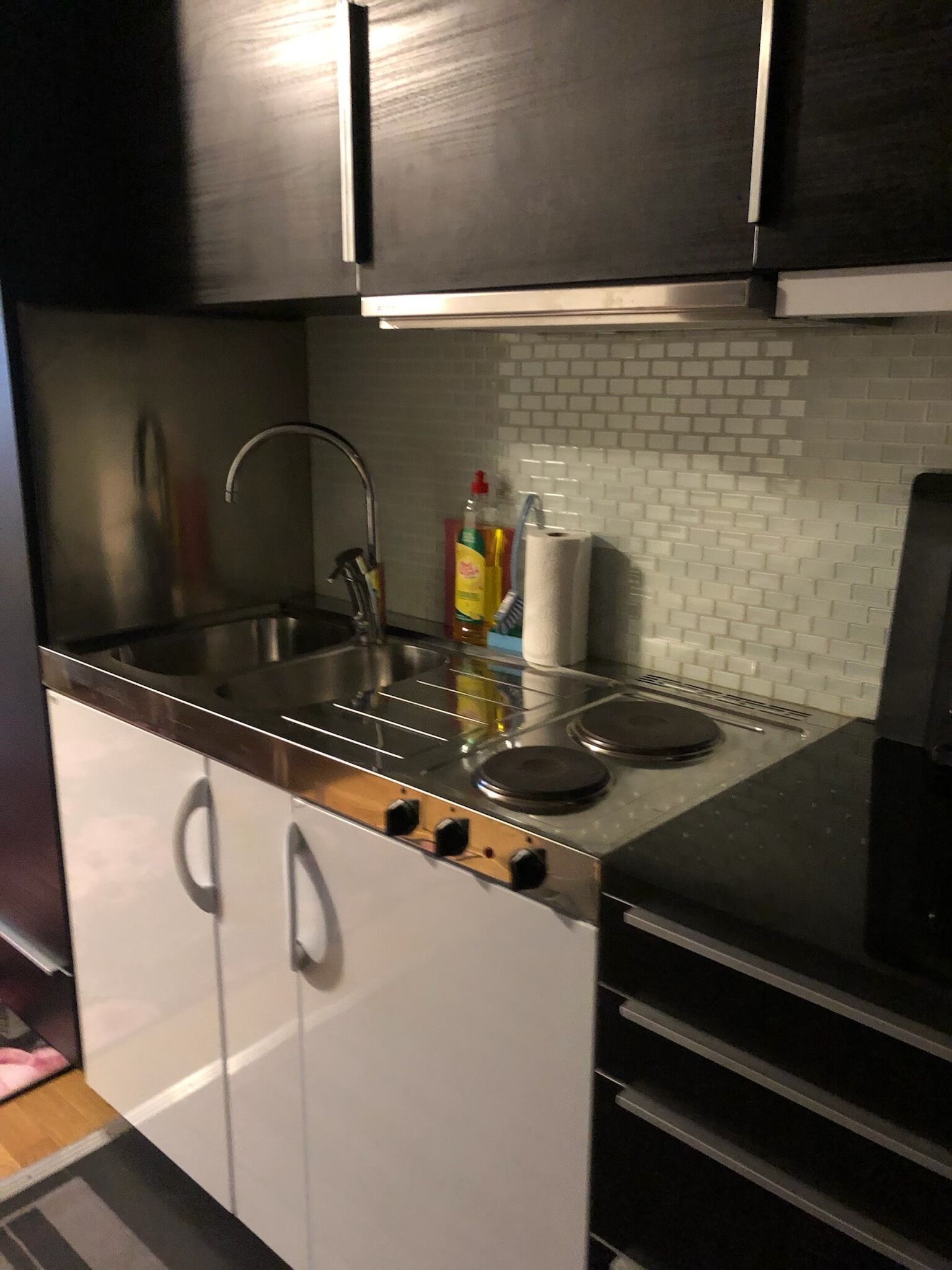 A modern kitchen with stainless steel appliances, a white tiled backsplash, and a black countertop.