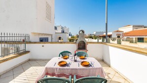 Terraço no telhado com uma mesa posta para dois, vista da cidade e uma chaminé.