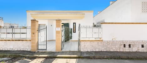 A gated entrance to a building with a stone wall and a metal gate.