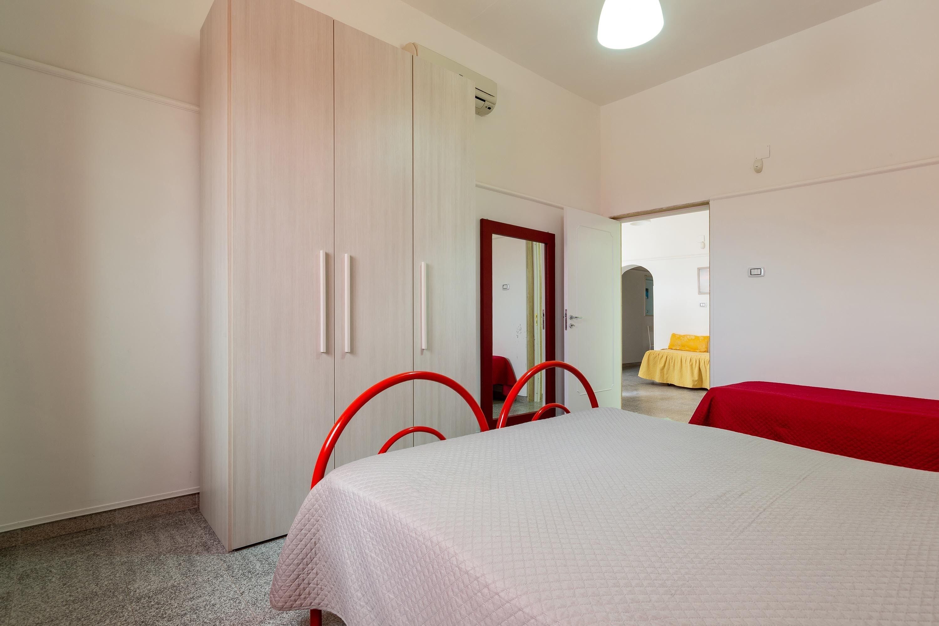 Ein Schlafzimmer mit einem Bett, einem Kleiderschrank und einem roten Sessel.