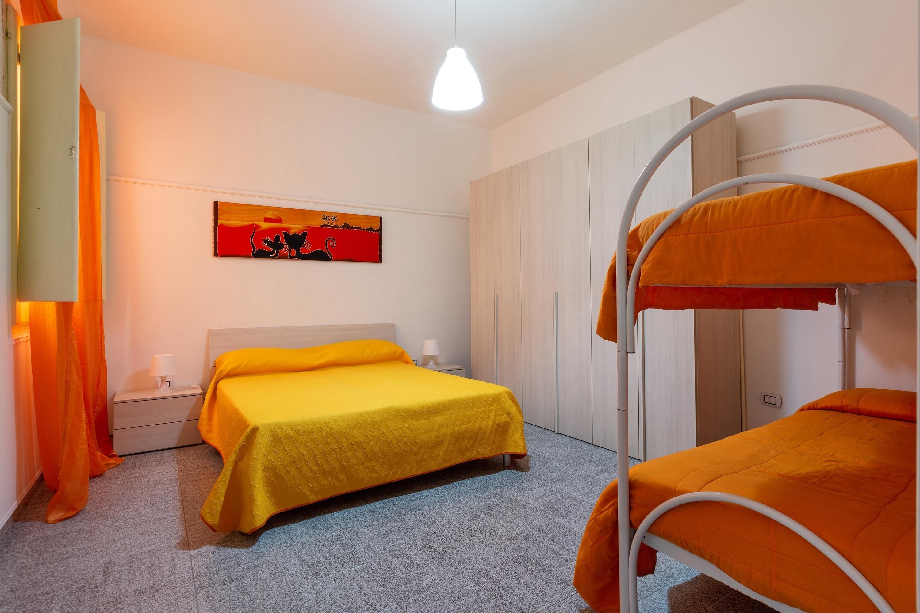 A room with a bunk bed, a single bed, a nightstand, a lamp, and a painting on the wall.