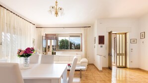 Una habitación luminosa y bien iluminada con una mesa de comedor, sillas, un sofá y un ventanal con cortinas.