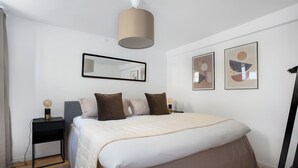 A bedroom with a bed, bedside tables, a mirror, and abstract wall art. - Regent 1 - Lovely 2-bdr Apt w Terrace (Copenhagen)