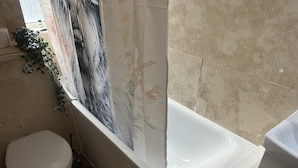 A bathroom with a bathtub, toilet, and a window with curtains. - Marble Arch Family Apartments Posh Central London (London)