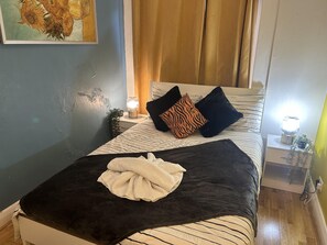 A neatly made bed with a striped bedspread, two pillows, a folded towel, and bedside lamps on nightstands.