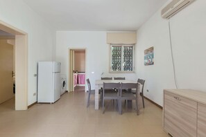 A compact kitchen with a washing machine, a dining table with chairs, and a wooden cabinet.