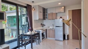 A modern kitchen with a dining area, a refrigerator, and a window with a view of greenery. - B204 - 1 Bdr Condo With Sea View, Ao Nang Beach (Krabi)