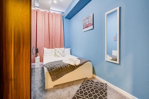 Une chambre à coucher avec un lit, un miroir et un tableau accroché au mur.