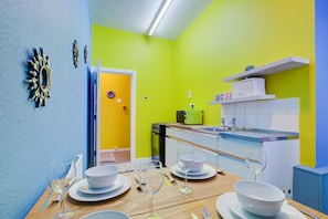 Une cuisine moderne avec un coin repas aménagé pour quatre personnes, comprenant une table en bois, des assiettes blanches et des verres à vin.