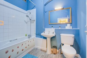 Bathroom features a bathtub, sink, and toilet, with decorative tiles and a gold-framed mirror.