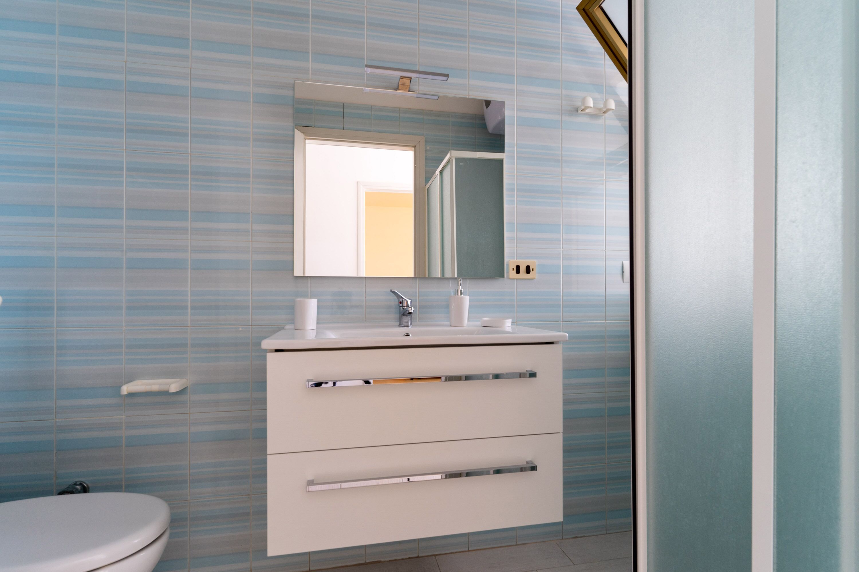 A bathroom with a white sink, mirror, and a toilet.