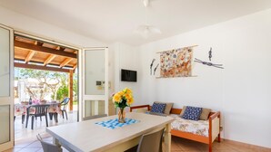 A room with a dining table, chairs, a sofa, and a TV on the wall. - 2960 Villetta Stella Mary - Bilo 2 by Barbarhouse (Nardò)