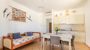 A compact living space with a sofa, dining table, and kitchen area. - 2960 Villetta Stella Mary - Bilo 2 by Barbarhouse (Nardò)