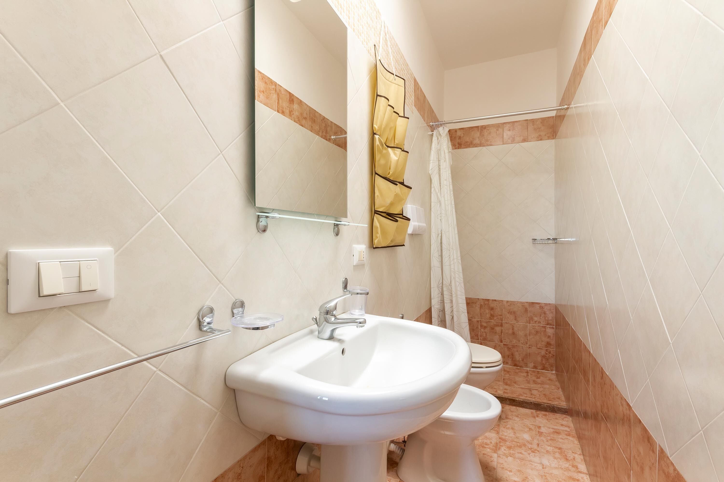 A bathroom with a white sink, a toilet, a shower with a glass door, and a mirror above the sink.