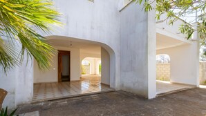 A spacious courtyard with a tiled floor, white walls, and arched doorways. - 2922 Villetta Marelia by Barbarhouse (Porto Cesareo)