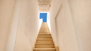 A narrow, beige staircase leading upwards, flanked by plain white walls, with a clear blue sky visible at the top. - 3003 Masseria Surani Grande- Appartamento Sinistra by Barbarhouse (Manduria)