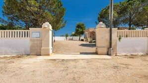 A gated entrance with a sign reading "Dora," leading to a building with a stone facade and a clear blue sky in the background.