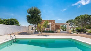 A swimming pool with a stone structure and trees in the background.