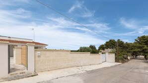 A residential street with a house featuring a tiled roof, a beige wall, and a visible entrance. - 3064 Villa La Fenice by Barbarhouse (Avetrana)