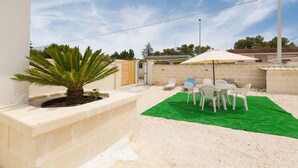 A patio area with a green carpet, white chairs, and a palm tree. - 3064 Villa La Fenice by Barbarhouse (Avetrana)