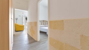 A hallway leading to a bedroom with a bed and a yellow chair. - 3064 Villa La Fenice by Barbarhouse (Avetrana)