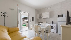 A modern kitchen with white cabinets, a microwave, and a washing machine. There is a dining area with white chairs and a table. - 3064 Villa La Fenice by Barbarhouse (Avetrana)