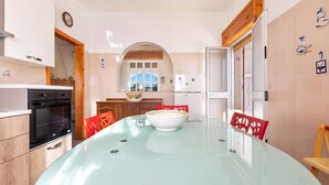 A modern kitchen with a glass dining table, wooden cabinets, and a red chair. - 2671 Villetta Holly by Barbarhouse (Lizzano)
