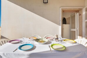 Una mesa redonda preparada para una comida, con platos, vasos y cubiertos de colores.