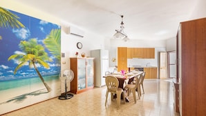 A spacious kitchen with wooden cabinets, a dining area with a table and chairs, and a large wall mural of a beach scene. - 3028 Villino Dolceluna by Barbarhouse (Porto Cesareo)