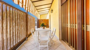 A covered patio with a table and chairs, a wooden fence, and a door. - 3028 Villino Dolceluna by Barbarhouse (Porto Cesareo)