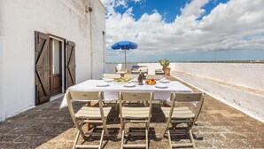 An outdoor dining area with a table set for four, a blue umbrella, and a view of the countryside. - 3002 Masseria Surani Grande- Appartamento Destra by Barbarhouse (Manduria)