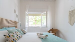 A neatly arranged bedroom with a bed, pillows, a chair, and a view through a window. - 2473 Villetta Seaside by Barbarhouse (Porto Cesareo)