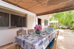 An outdoor dining area with a covered table set for four, surrounded by wooden chairs and a bench. - 2473 Villetta Seaside by Barbarhouse (Porto Cesareo)