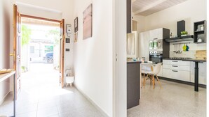A modern kitchen with white cabinets, a central island, and a dining area with a chair. - 2473 Villetta Seaside by Barbarhouse (Porto Cesareo)