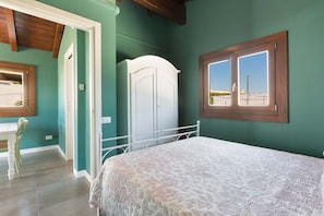 A bedroom with a bed, a wardrobe, a window, and a door.