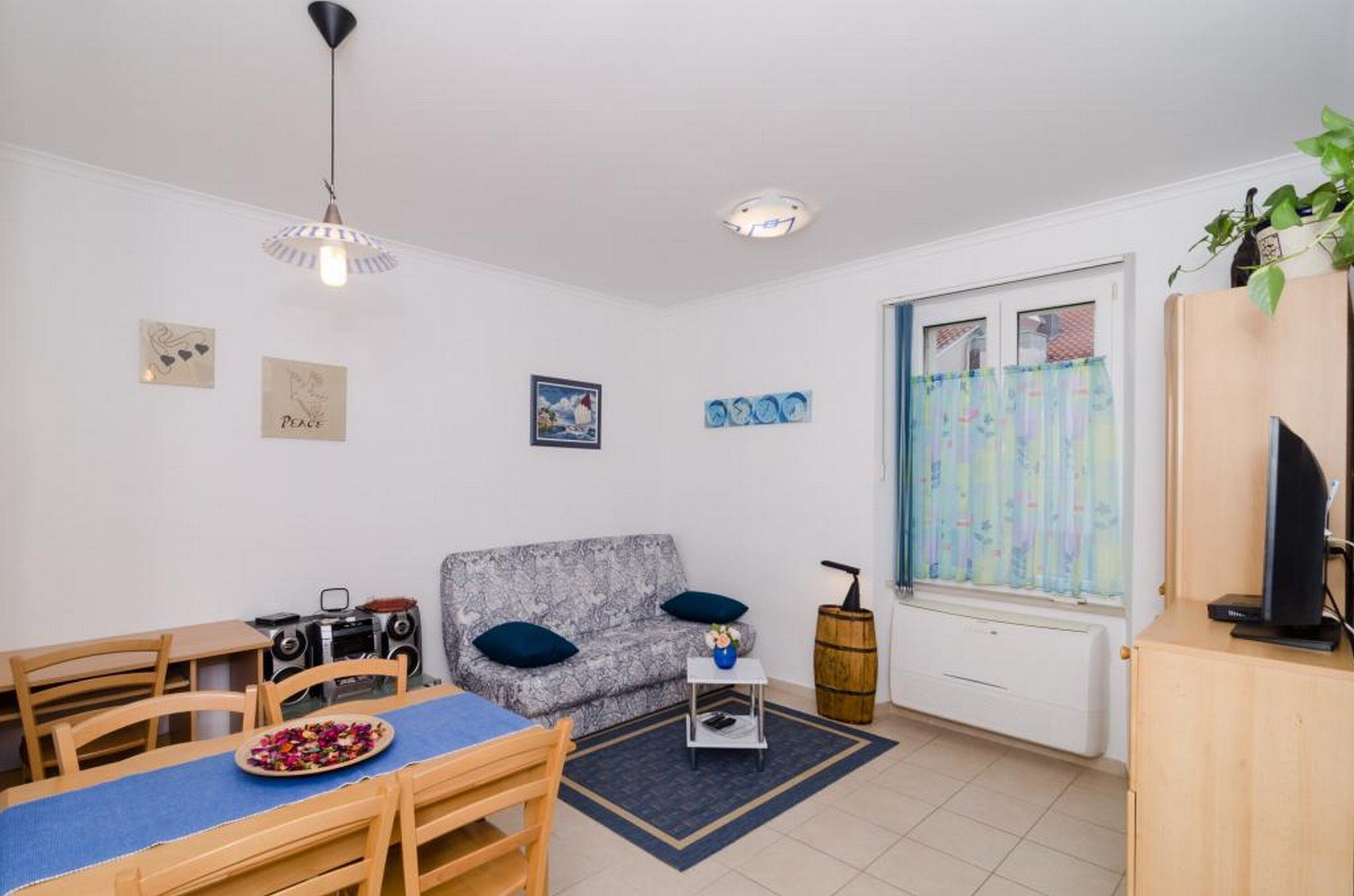 A cozy living room with a sofa, a dining table, and a television.