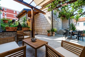An outdoor patio with wooden furniture, potted plants, and a stone wall. - Apartments & Room Frane (Dubrovnik)