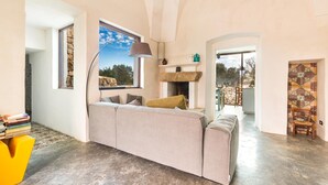 A spacious living room with a large beige sofa, a fireplace, and a view of the outdoors. - 2670 Trullo Corni di Fiasco by Barbarhouse (Maruggio)