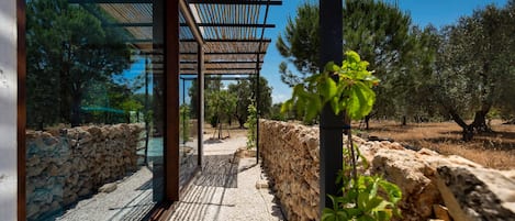 Un espacio exterior moderno con una pérgola, paredes de piedra y un camino de grava.