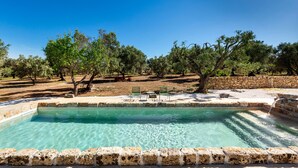 A clear pool with a stone border, surrounded by trees and a stone wall. - 2670 Trullo Corni di Fiasco by Barbarhouse (Maruggio)
