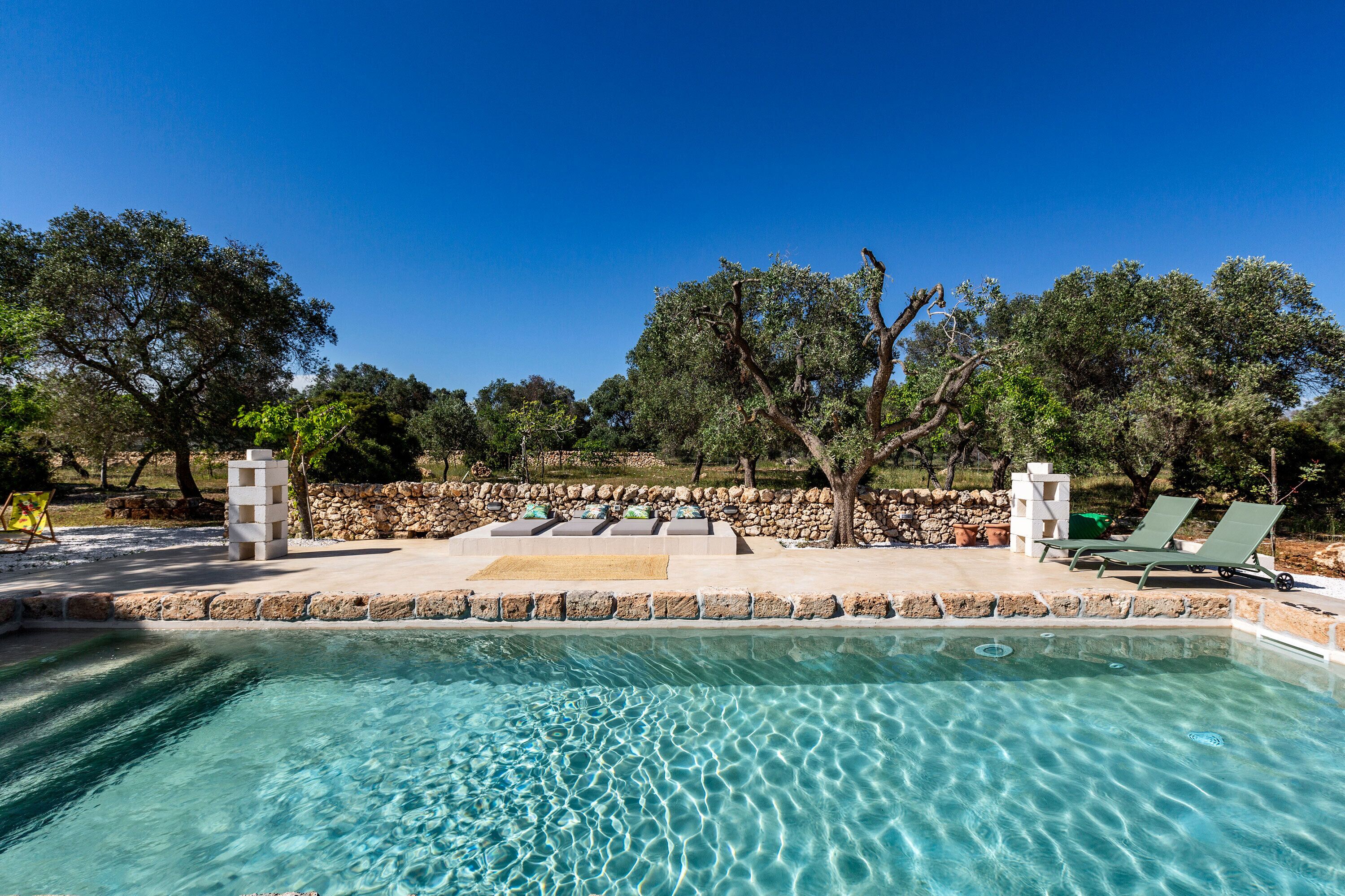 Ein klarer Pool mit Liegestühlen und einer Steinmauer.